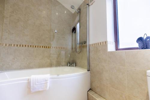 a bathroom with a bath tub and a sink at GARDEN FIELD COTTAGE - Spacious Holmbridge Home with Rolling Hill Views in Holmbridge