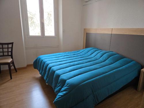 a blue bed in a room with a window at Logis Belledonne in Arvillard