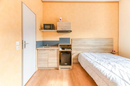 a small bedroom with a bed and a microwave at Logis Belledonne in Arvillard