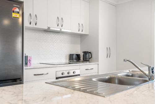 a kitchen with a sink and a stainless steel refrigerator at New Stylish Family Escape with Deck - 7 mins to MONA in Austins Ferry