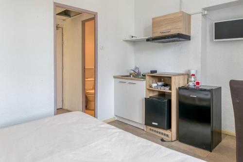 a small kitchen with a black refrigerator in a room at Logis Belledonne in Arvillard