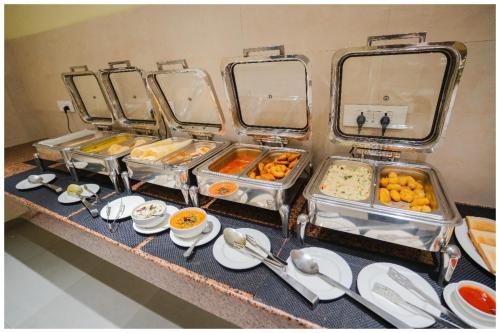 a buffet with several trays of food on a table at Hotel Q Saina Aarokan Height Near Sea Beach And Jagannath Temple Puri in Puri