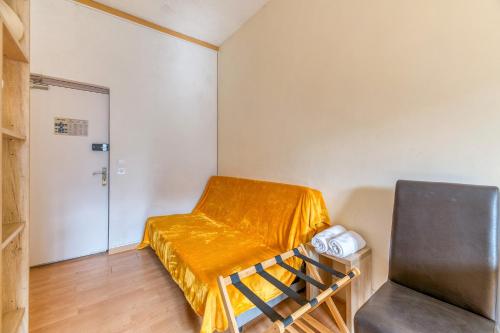 a small room with a bed with a yellow sheet on it at Logis Belledonne in Arvillard