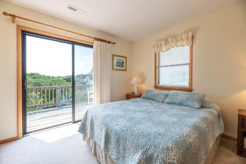 a bedroom with a bed and a large window at Persimmon in Duck
