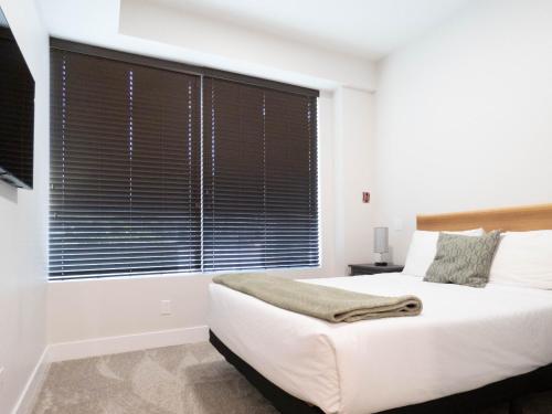 a bedroom with a large window with black blinds at Beach Suites in Parksville