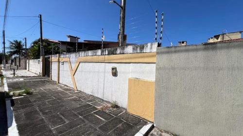 an empty sidewalk next to a wall with a fence at Casa Aconchegante in Natal