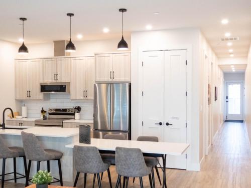 a kitchen with white cabinets and a table and chairs at Beach Suites in Parksville