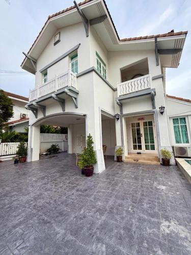 a large white house with a large driveway at Warisa Garden Pool Villa in Jomtien Beach