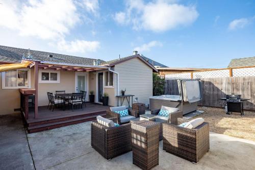 eine Terrasse mit Korbmöbeln und eine Terrasse mit Grill in der Unterkunft Charming Garden Cottage- steps to historic Old Town Half Moon Bay in Half Moon Bay