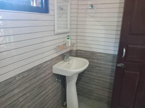a bathroom with a white sink and a mirror at Kahuwa Guest House in Kāziranga