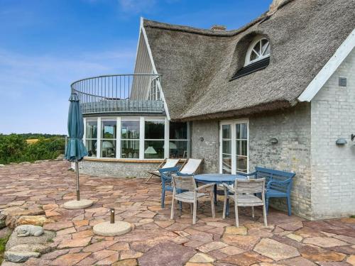 a patio with a table and chairs and an umbrella at Holiday Home Herlek - 450m from the sea by Interhome in Åkirkeby