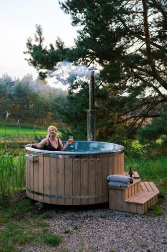 a woman sitting in a hot tub in a yard at Domki na Kaszubach z banią jacuzzi - Gołubie - Sikorska Dolina III in Stara Sikorska Huta