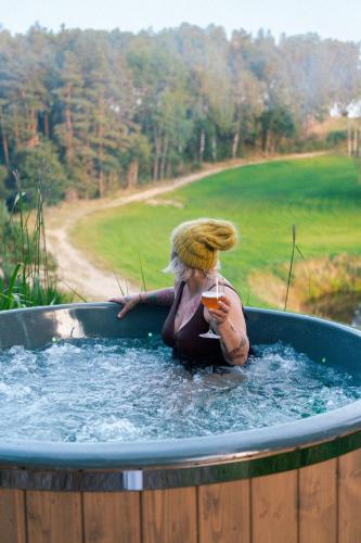 a woman is sitting in a hot tub at Domki na Kaszubach z banią jacuzzi - Gołubie - Sikorska Dolina III in Stara Sikorska Huta