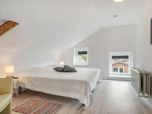 a white bedroom with a bed and two windows at Holiday Home Aliza - 14km from the sea by Interhome in Bredebro