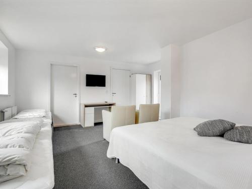 a white bedroom with two beds and a desk at Holiday Home Aliza - 14km from the sea by Interhome in Bredebro
