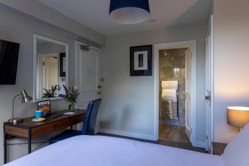 a bedroom with a bed and a desk and a table at Whately Hall Hotel in Banbury