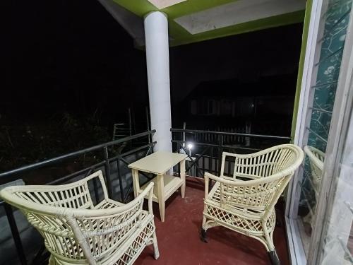 two chairs and a table on a balcony at night at Mountain View Private Villa in Ooty