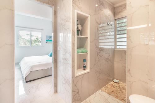 a bathroom with a walk in shower next to a bed at Villa Mangorient 3 bd private pool in Orient Bay in Orient Bay