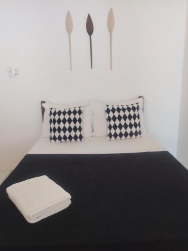 a bedroom with a bed with black and white pillows at Pouso Paraty in Paraty