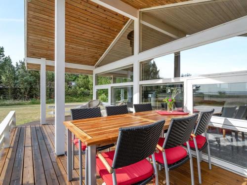 an outdoor patio with a wooden table and chairs at Holiday Home Eltje - 4km from the sea by Interhome in Blåvand