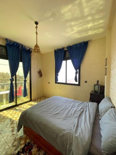a bedroom with a bed with blue curtains and a window at Island surf house in Imsouane