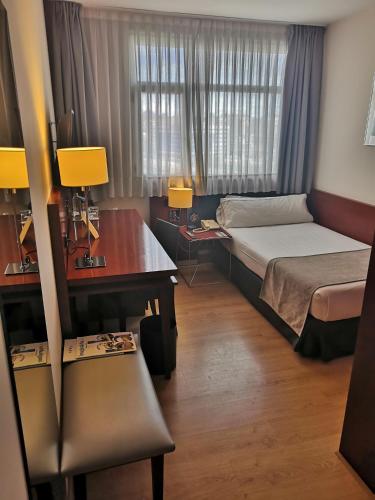 a hotel room with a bed and a desk and a desk at Abba Euskalduna Hotel in Bilbao