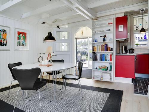 a kitchen with red cabinets and a white table and chairs at Holiday Home Solfrid - 150m from the sea by Interhome in Esbjerg