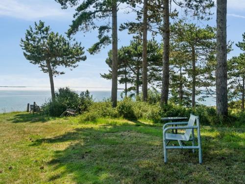 a bench sitting in the grass near the water at Holiday Home Uschi - 86m from the sea by Interhome in Kalundborg