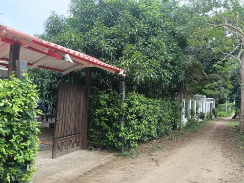 a small building with a red roof next to a dirt road at Cabaña velez in Capurganá
