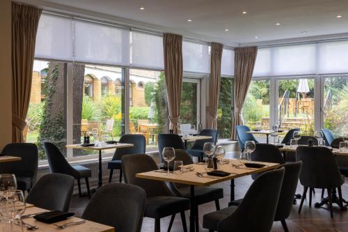 a restaurant with tables and chairs and large windows at Whately Hall Hotel in Banbury