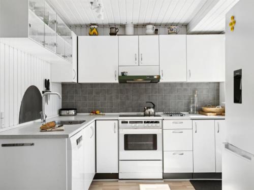 a white kitchen with white cabinets and appliances at Holiday Home Manfred - 250m from the sea by Interhome in Rønde