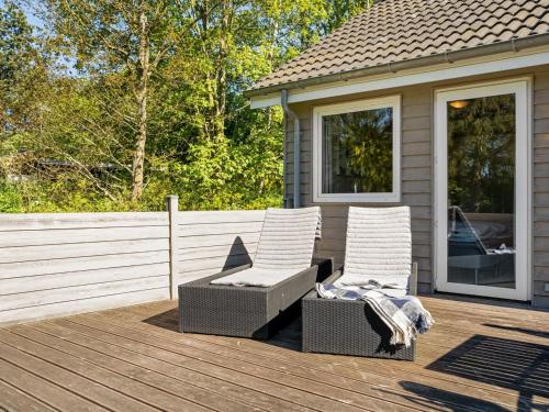 two chairs sitting on a deck next to a house at Holiday Home Rohan - 700m from the sea by Interhome in Rødby