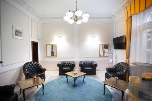 a waiting room with chairs and tables and a chandelier at Hotel Ester in Karlovy Vary