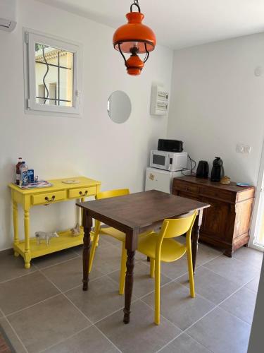 a kitchen with a wooden table and yellow chairs at Gîtes Violettes et Amandier in Violès