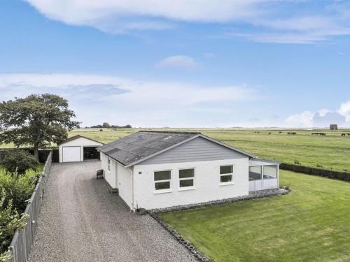 a white house in a field with a fence at Holiday Home Janin - 400m from the sea by Interhome in Højer