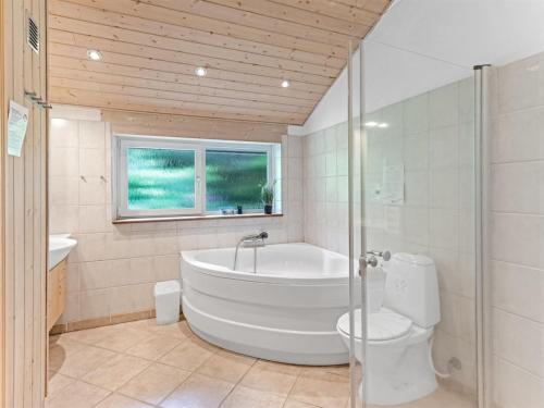 a bathroom with a tub and a toilet and a window at Holiday Home Samine - 2km from the sea by Interhome in Bøstrup