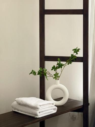 a white vase sitting on a wooden shelf with a plant at Little Chái Nho - The Flow in Da Lat