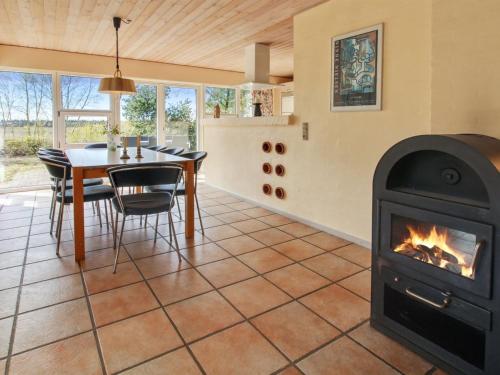 a fireplace in a dining room with a table and a stove at Holiday Home Alina - 1km from the sea by Interhome in Mølby