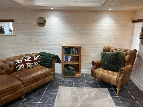 a living room with two leather couches and a book shelf at Cozy Seaside Retreat in Peterhead in Boddam