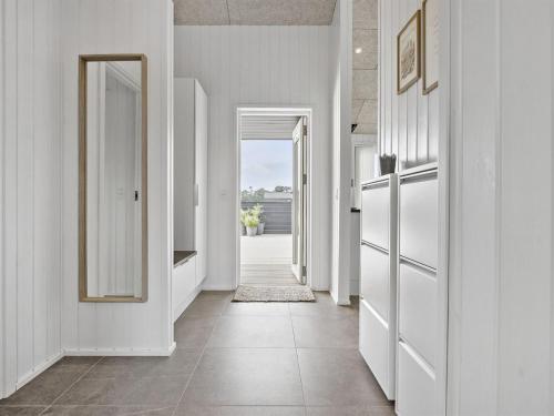 a hallway with white walls and white doors and a tile floor at Holiday Home Frithbjorn - 900m from the sea by Interhome in Jerup