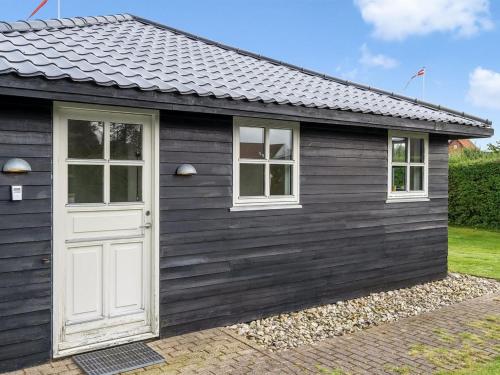 a black shed with a white door and two windows at Apartment Söhnke - 600m from the sea by Interhome in Aså