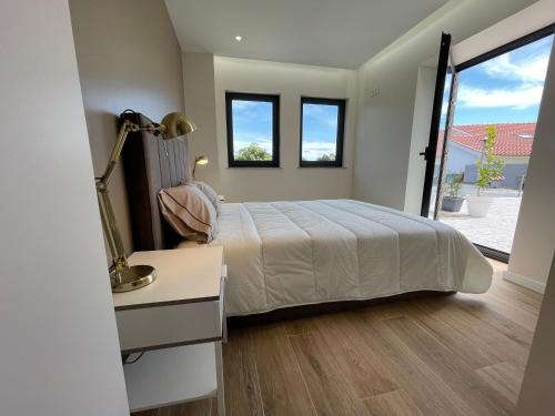 a bedroom with a bed and a desk and windows at Living Viana do Castelo in Viana do Castelo