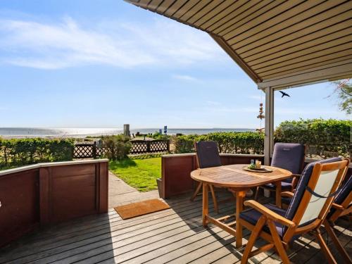 a patio with a wooden table and chairs and the ocean at Holiday Home Anselmi - 25m from the sea by Interhome in Sjølund