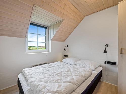 a bedroom with a large bed with a window at Holiday Home Botmar - 1-5km from the sea by Interhome in Ringkøbing