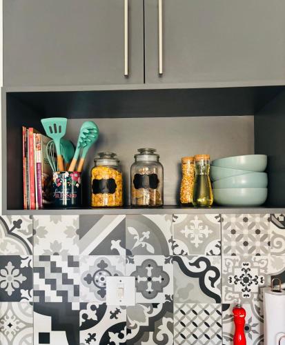 a kitchen shelf with bowls and utensils on it at Tubungu- House of Lux& Lush in Matsapha