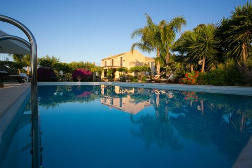 a large swimming pool with palm trees and a house at Baglio Sant'Andrea in Valderice