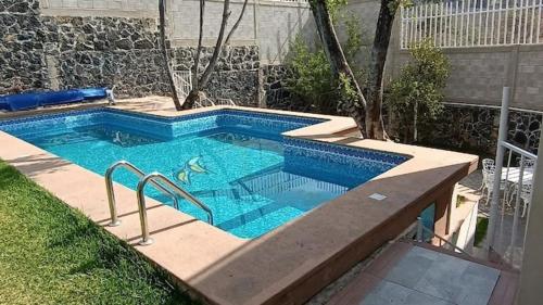 a swimming pool with blue water in a yard at Casa Marcy, casa nueva con alberca y tres recamaras in Pazulco