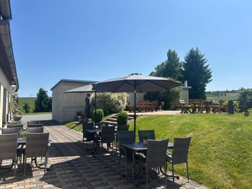 a patio with tables and chairs and an umbrella at Pension und Café "Alte Straßenmeisterei" in Hasselfelde