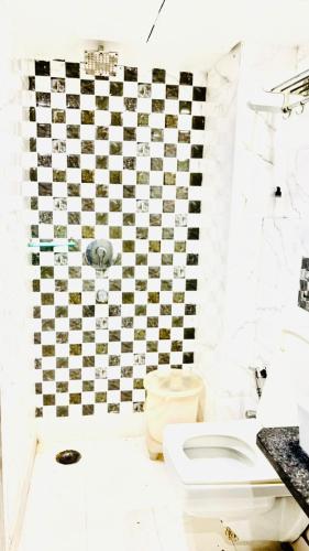 a bathroom with a black and white checkered wall at Saffron By Family Hotels - Main Market New Delhi in New Delhi