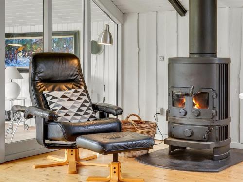 Un sillón de cuero negro y una chimenea en la sala de estar en Holiday Home Magnus - 250m to the fjord by Interhome, en Esbjerg